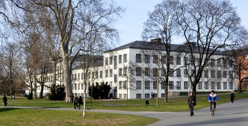 Herrngarten in Darmstadt mit Spaziergängern und Radfahrer, im Hintergrund das Robert-Piloty-Gebäude der TU Darmstadt