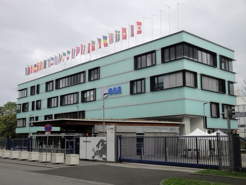 Türkisfarbenes Gebäude des ESA-Raumflugkontrollzentrums ESOC in Darmstadt mit einer Reihe von Länderflaggen auf dem Dach