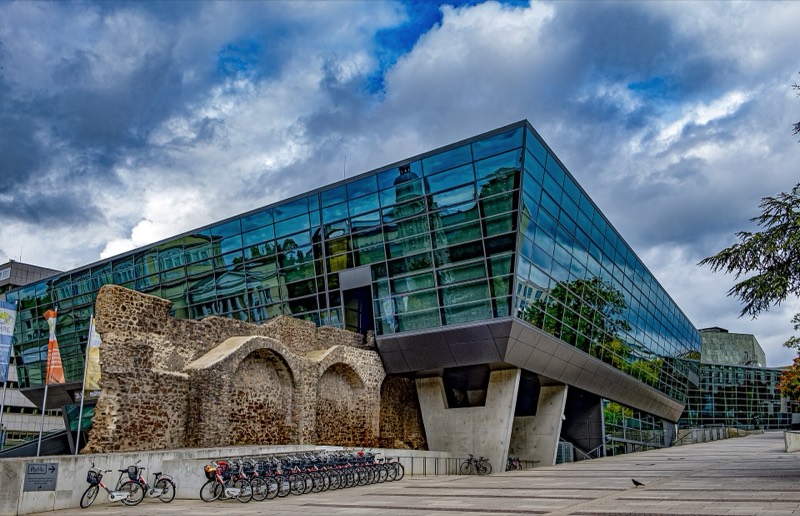Das gläserne Kongresszentrum darmstadtium in Darmstadt mit Resten der alten Stadtmauer und Fahrradständern davor