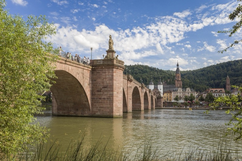 Alte Brücke über den Neckar in Heidelberg mit Brückentor, Heiliggeistkirche und bewaldetem Hang im Hintergrund – Ziel der E-Bike-Tour entlang der Bergstraße