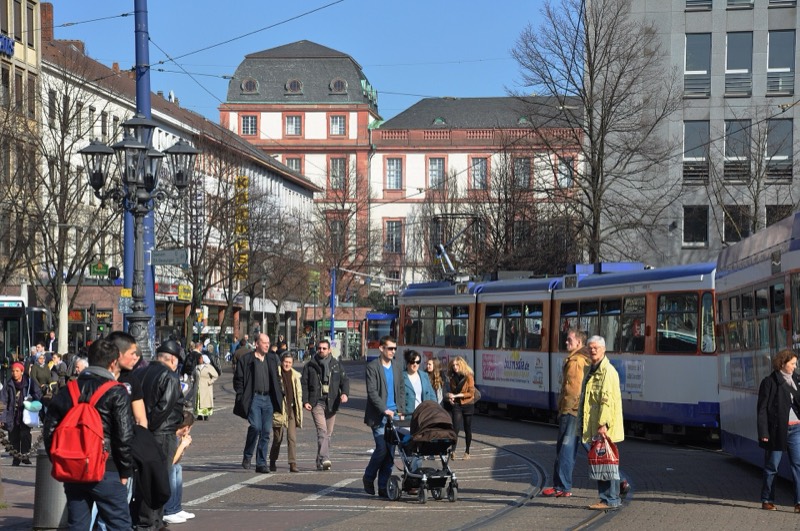 Luisenplatz in Darmstadt mit Straßenbahnen, Passanten und Blick zum Residenzschloss