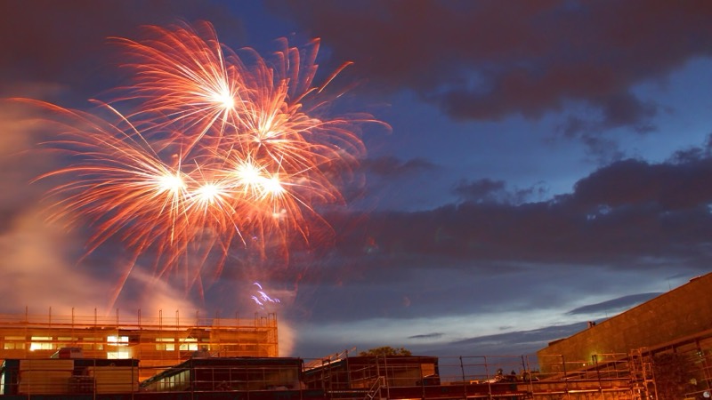 Rotes Feuerwerk über Darmstadt in der Abenddämmerung, im Vordergrund eingerüstete Gebäude