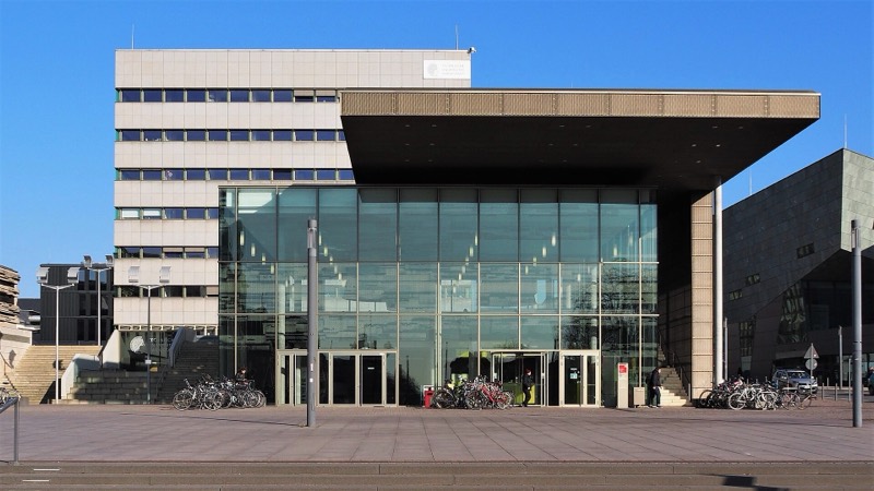 Eingangsgebäude „karo 5“ der TU Darmstadt am Karolinenplatz mit gläserner Fassade, auskragendem Dach und Fahrrädern davor